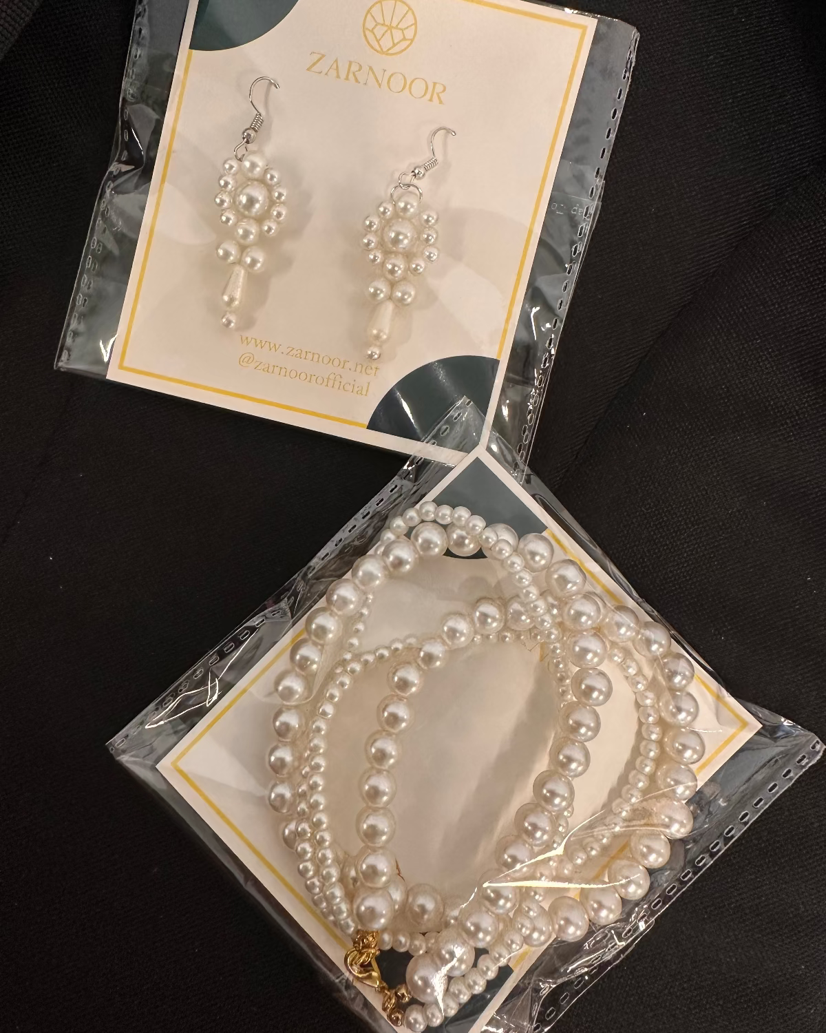 Pearl necklace and earrings set with Zarnoor packaging on a dark background
