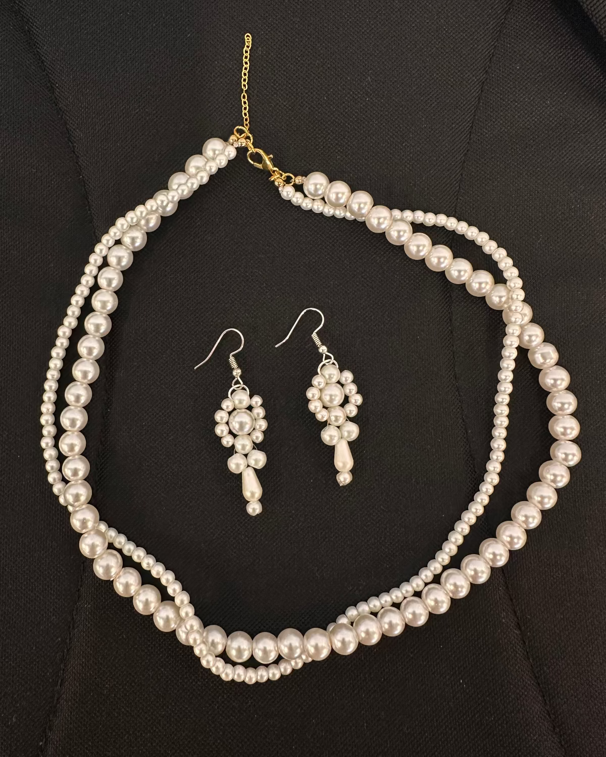 Pearl necklace and earrings set on a black background