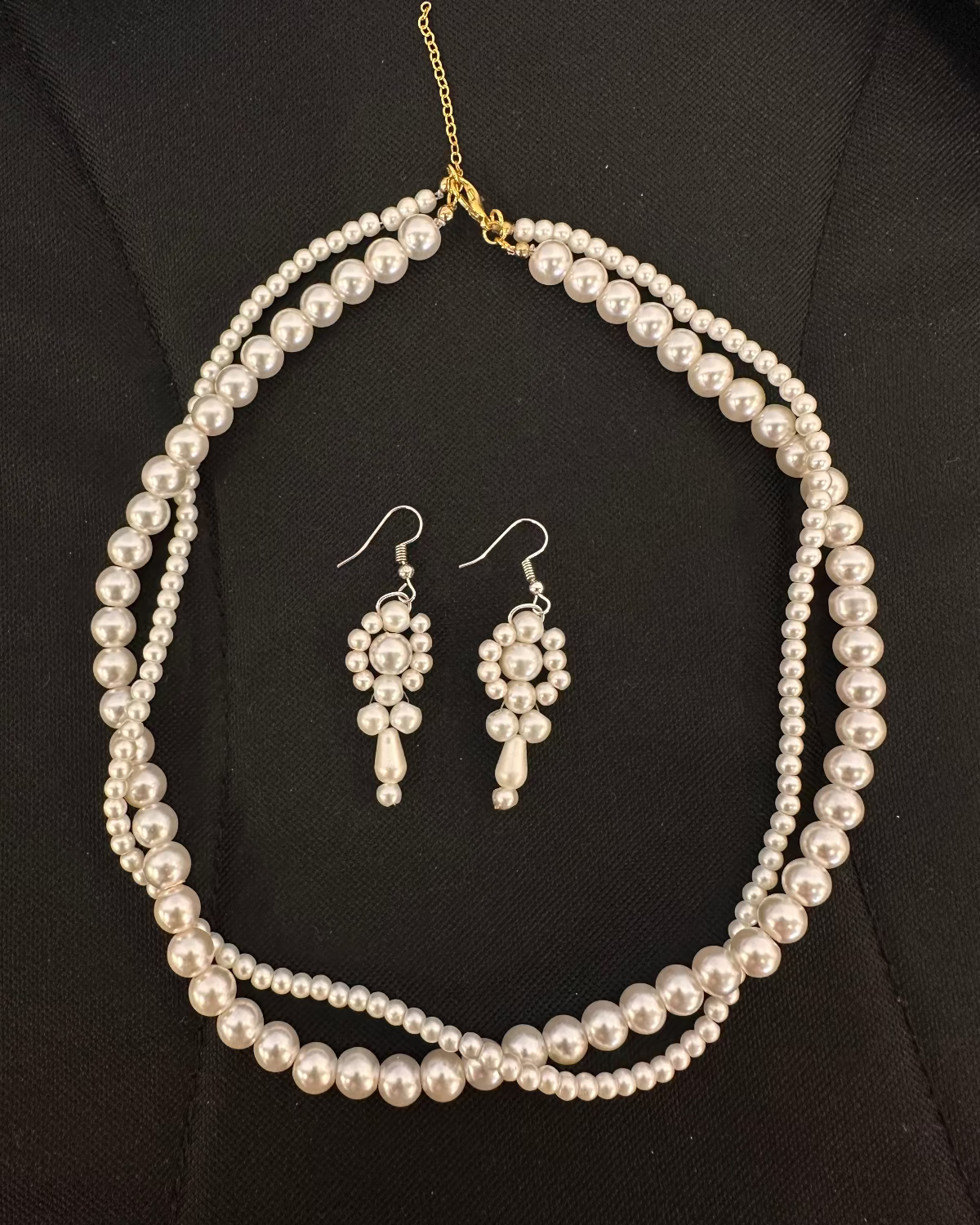 Pearl necklace and earrings set on a black background