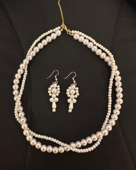 Pearl necklace and earrings set on a black background