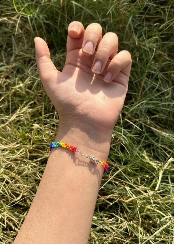 Hand with a colorful bracelet against a grassy background