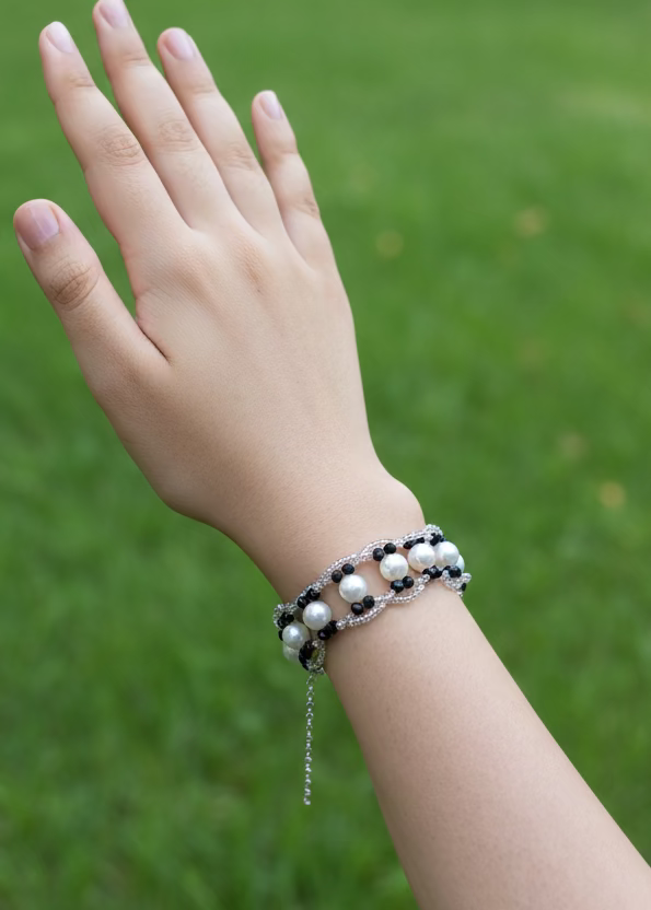 Hand wearing a bracelet with pearls against a plain background