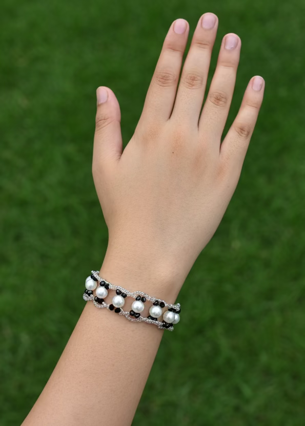 Hand wearing a bracelet on a plain background
